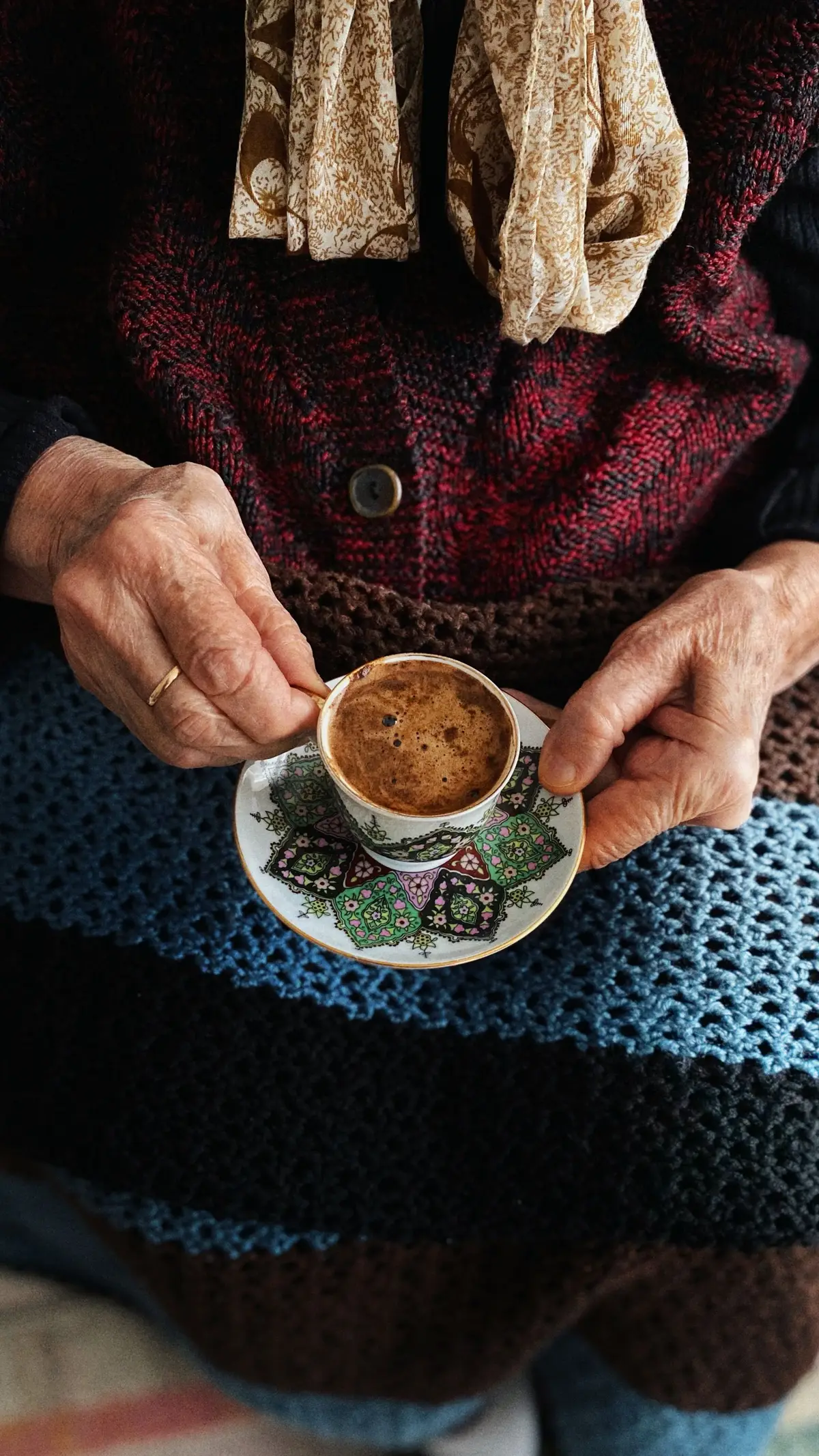 Hände einer älteren Person halten eine Tasse Kaffee
